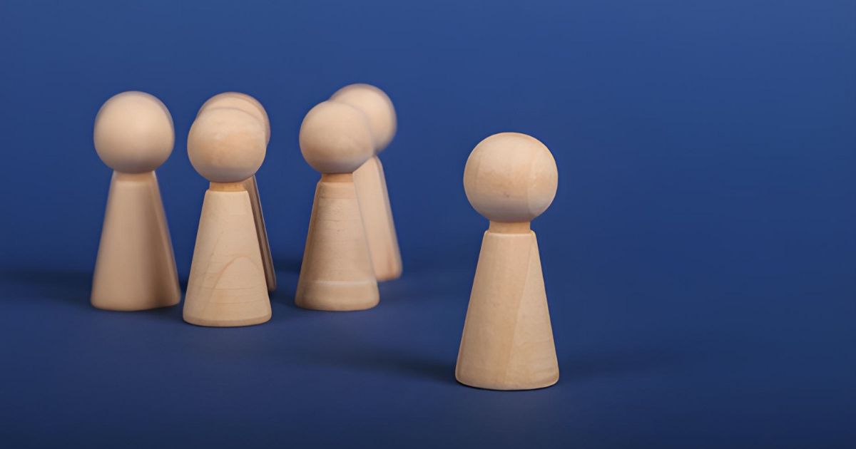 One wooden peg standing apart from the clustered group on a navy blue background